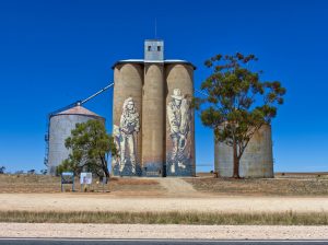 Photo of three silos in a field with artwork painted on them