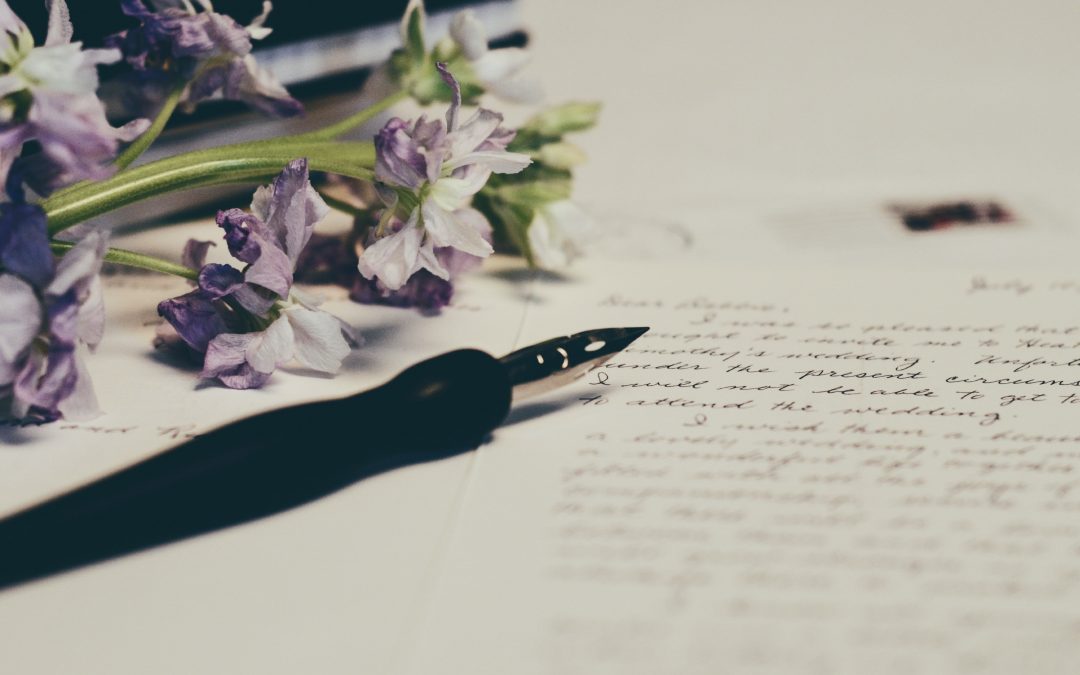 Fountain pen writing list of wishes with purple flowers beside
