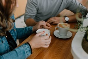 Friends or a couple holding hands while drinking coffee