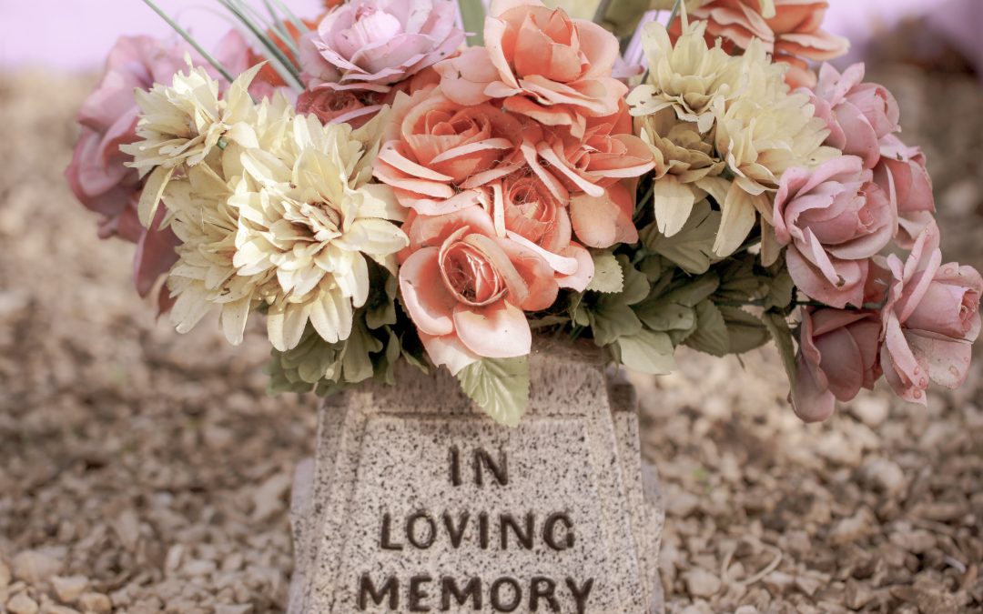 Flowers on a headstone reading 'in loving memory'