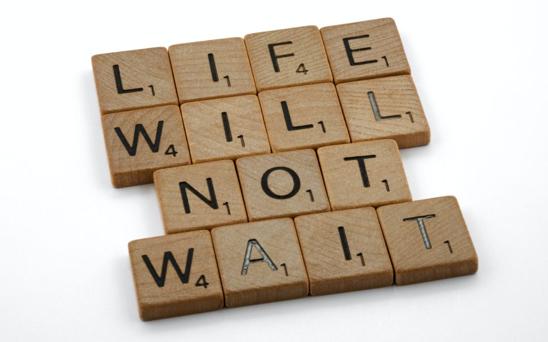 Scrabble tiles forming the words 'Life will not wait'